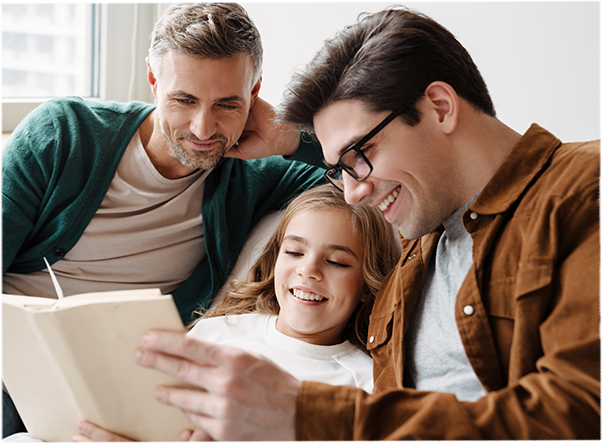 Two dads with daughter reading a book